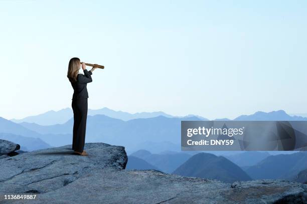 businesswoman with spyglass looking out toward mountain range - olhar através imagens e fotografias de stock