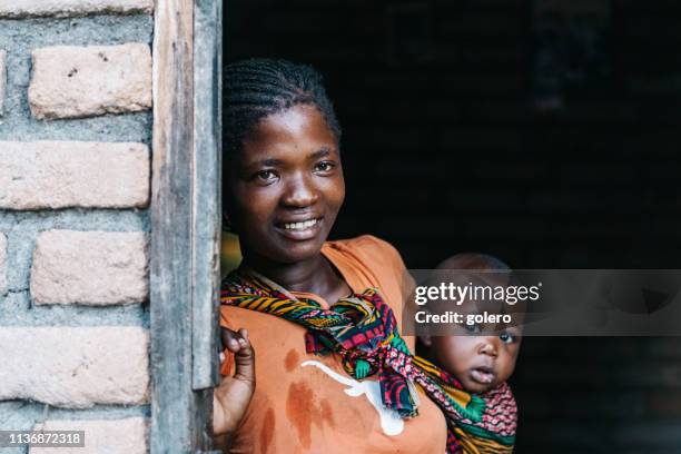 young african mother with baby standing in the door - african ethnicity family africa stock pictures, royalty-free photos & images