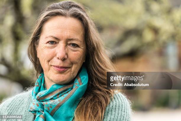portrait of a beautiful senior woman with long hair in the garden, europe - donna 60 anni foto e immagini stock