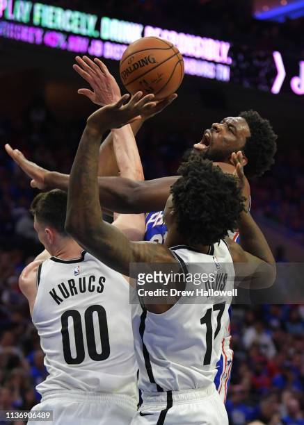 Joel Embiid of the Philadelphia 76ers tries to get a shot off over Rodions Kurucs and Ed Davis of the Brooklyn Nets in the second half during Game...
