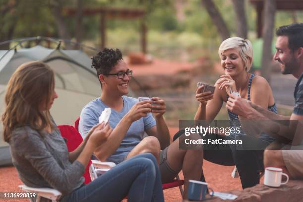 four millennial friends play cards at their campsite - the comedy tent stock pictures, royalty-free photos & images