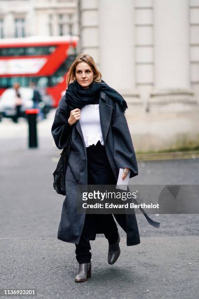 Guest wears a black scarf, a grey coat, a black top, black pants, a white smocked tube top, grey boots, during London Fashion Week February 2019 on...