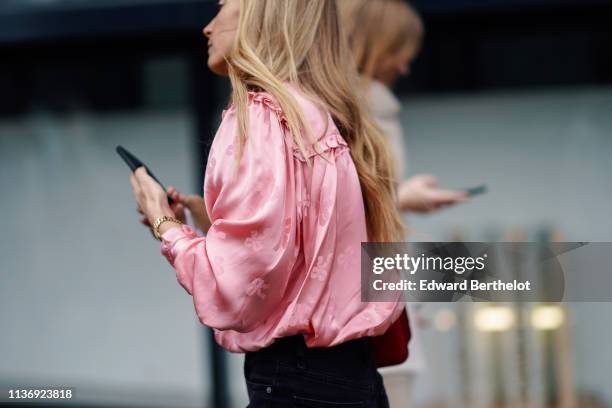 Guest wears a lustrous pink satin gathered top, during London Fashion Week February 2019 on February 16, 2019 in London, England.