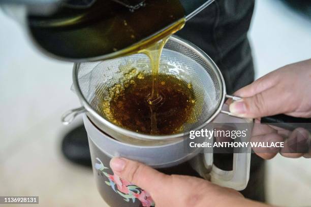 This photo taken on December 28, 2018 shows beekeeper Yip Ki-hok pouring freshly extracted honey from a honeycomb spinner drum as his son Hugo...