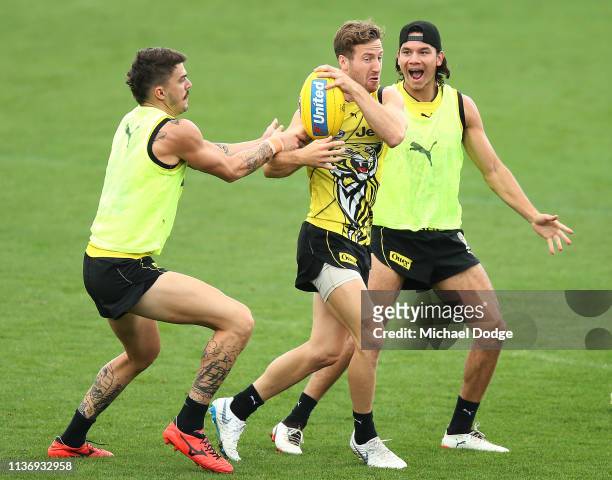 Kane Lambert of the Tigers is tackled by Oleg Markov as Daniel Rioli of the Tigers reacts during a Richmond Tigers AFL training session at Punt Road...