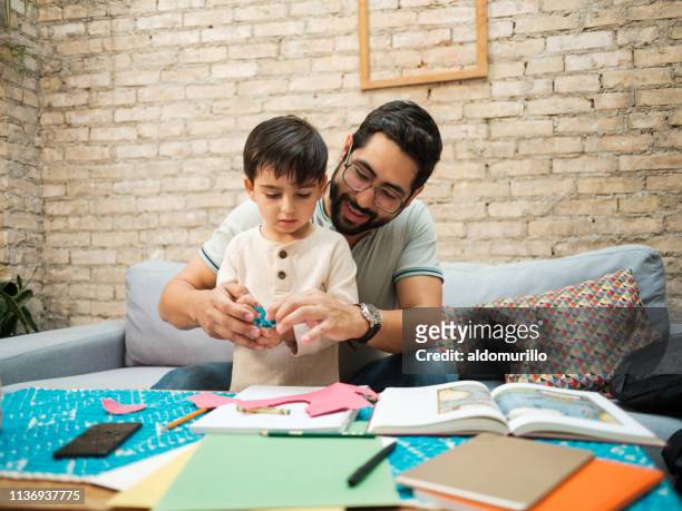happy mexican father helping little boy to use pair of scissors - latin america family stock pictures, royalty-free photos & images