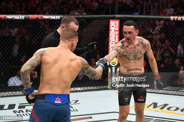 Dustin Poirier and Max Holloway meet in the middle of the Octagon in their interim lightweight championship bout during the UFC 236 event at State...
