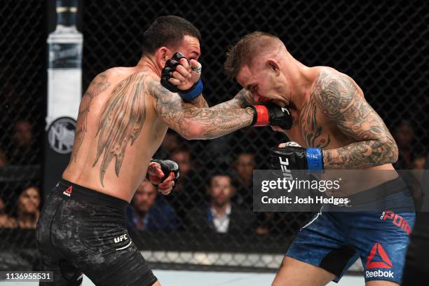 Max Holloway punches Dustin Poirier in their interim lightweight championship bout during the UFC 236 event at State Farm Arena on April 13, 2019 in...