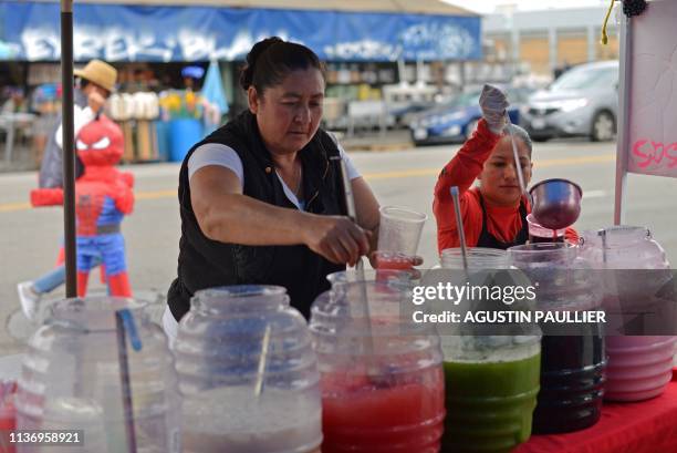 Angelica Rodriguez and Merli Son serve juice to customers from a street vending stand in the Pinata District in Downtown Los Angeles on March 23,...