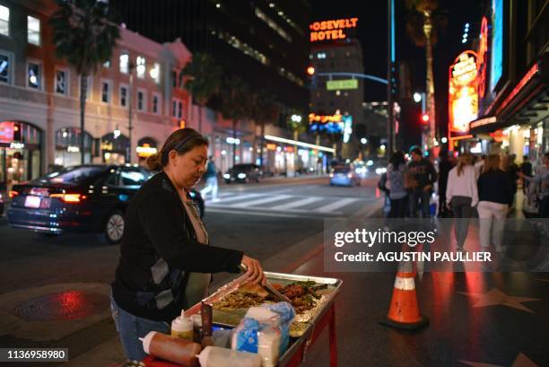 Maria Navas prepares hot dogs in front of the Dolby Theatre on the Hollywood Walk of Fame, in Los Angeles, on March 18, 2019. - Navas arrived to the...