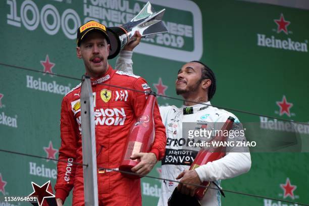 Mercedes' British driver Lewis Hamilton celebrates on the podium while joking around with third-placed Ferrari's German driver Sebastian Vettel and...