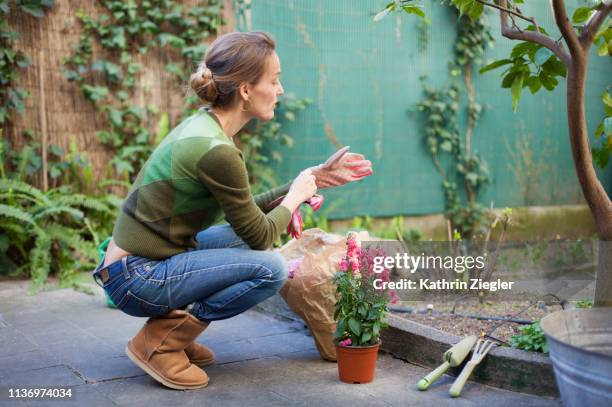 woman planting flowers in her backyard, rome, italy - accroupi profil photos et images de collection