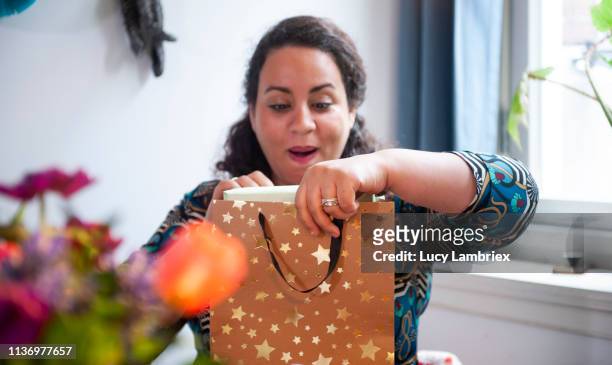 birthday girl is opening a gift bag with her present - sorpresa regalo foto e immagini stock