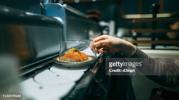 human's hand picking up sushi dish at sushi bar in the japanese restaurant - belt stock pictures, royalty-free photos & images