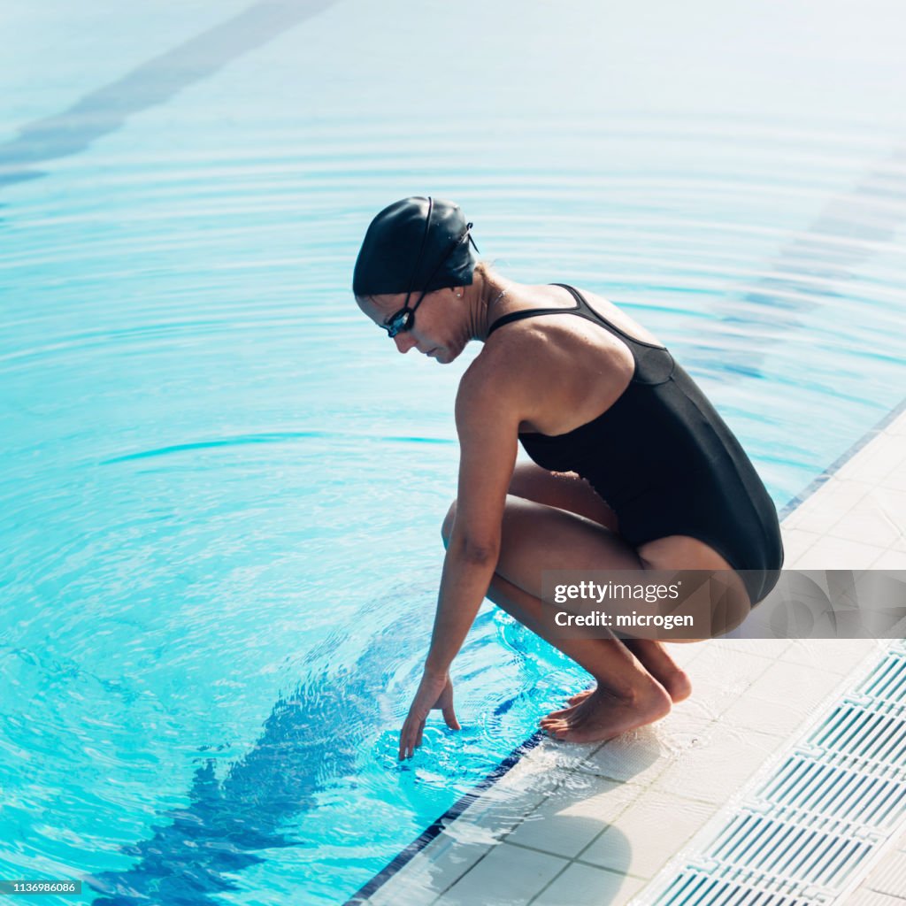 Pool Crounching Side View Of Woman Crouching By Swimming Pool High-Res Stock Photo ...