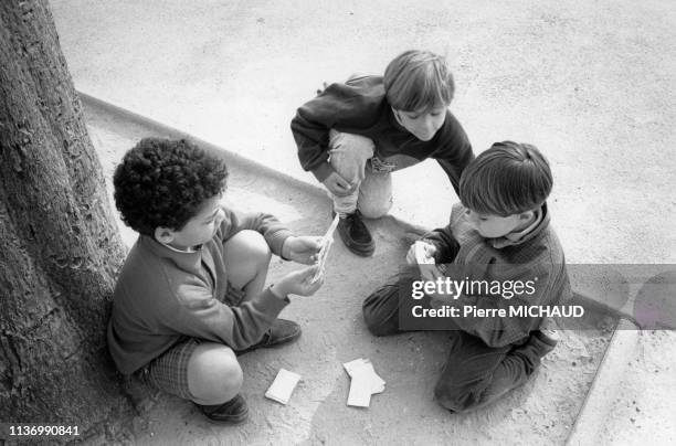 Enfants jouant au cartes dans la cour de récréation d'une école primaire à Paris, en 1989, France.