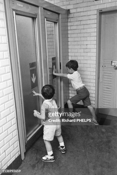Enfants poussant les portes de sortie d'une station de métro à Paris, en 1986, France.