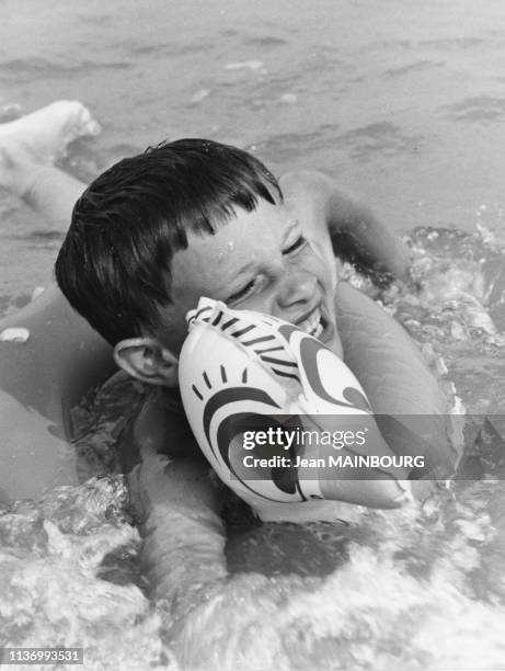 Enfant se baignant avec une bouée sur la plage, dans les années 1990, France.