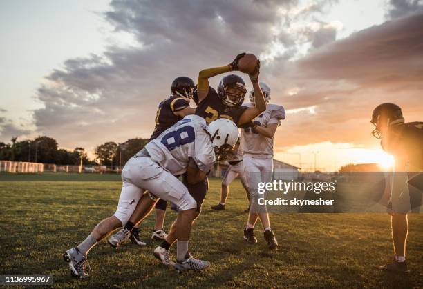 tackling an offensive player at sunset! - american football tackle stock pictures, royalty-free photos & images