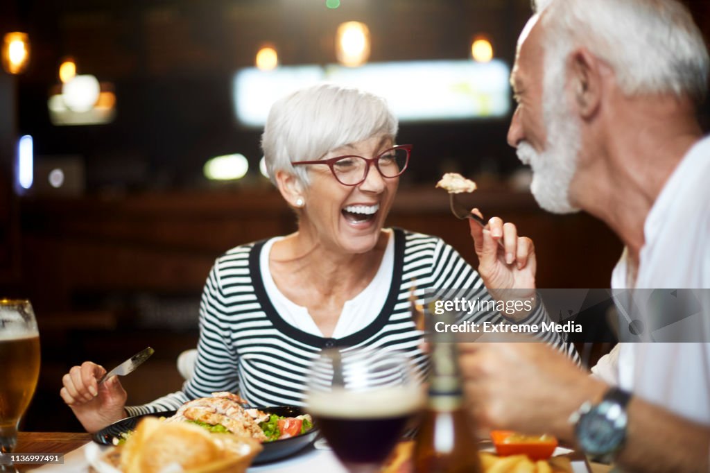 Senior couple feeding each other and having a good time during a meal in a restaurant