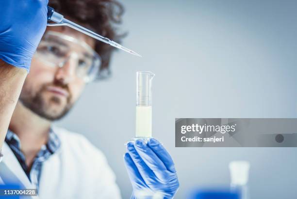 scienziato che lavora in laboratorio, usando pipette - reazione chimica foto e immagini stock