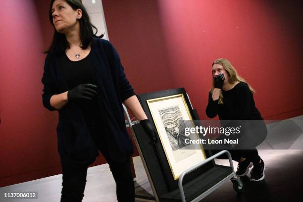 Gallery assistants discuss moving a lithograph print of "The Scream" by Edvard Munch during a photocall to promote the "Edvard Munch: love and angst"...