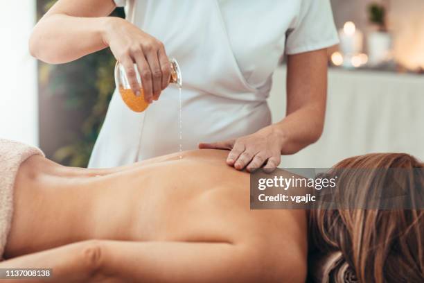 frau freut sich über golden oil massage - essential oil stock-fotos und bilder