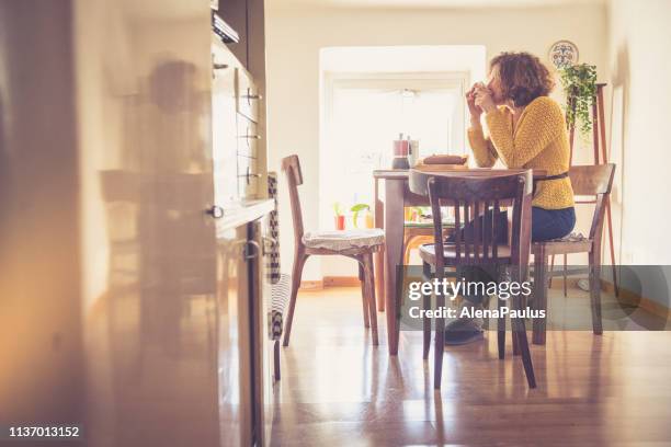 mulher nova que tem o pequeno almoço em sua cozinha - isolamento - fotografias e filmes do acervo