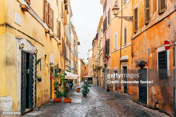 narrow cobbled street in trastevere neighborhood, rome, italy - italien stock-fotos und bilder