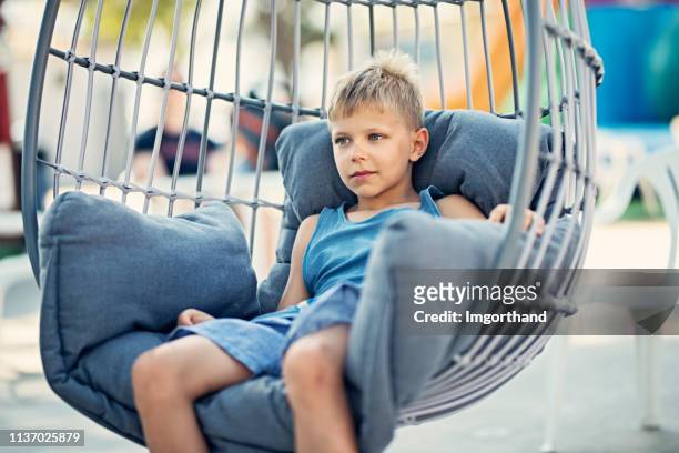 kleine jongen rusten comfortabel in opknoping ei stoel - egg chair stockfoto's en -beelden