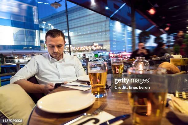 businessman using mobile phone and drinking beer in restaurant - ghosted stock pictures, royalty-free photos & images