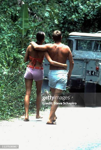 View, from behind, of American actors Ali MacGraw and Steve McQueen as they walk, arm in arm, on location at the set of McQueen's film 'Papillon' ,...