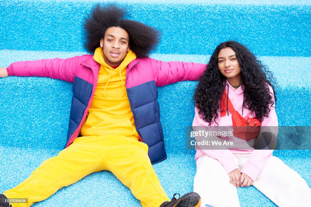 Fashionable couple sitting on blue floor