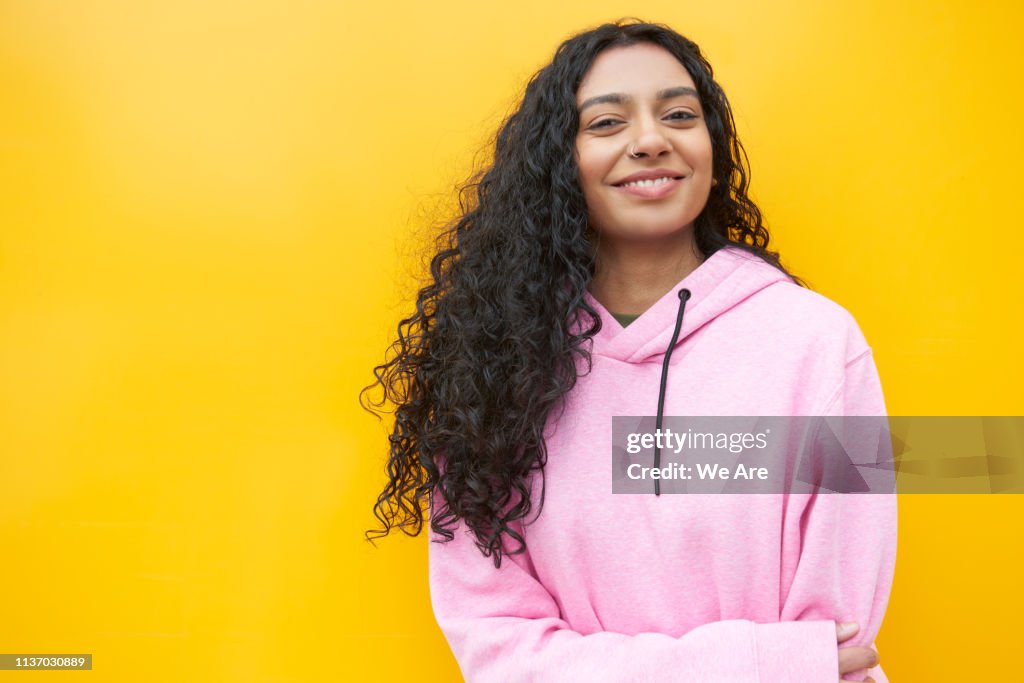 Portrait of young woman standing in front of a yellow background