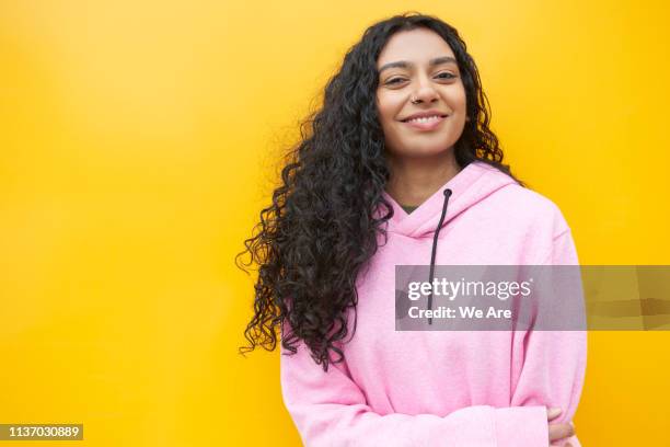 portrait of young woman standing in front of a yellow background - sweatshirt stock pictures, royalty-free photos & images
