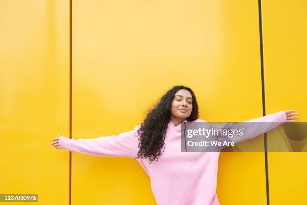 woman with arms outstretched against yellow background - color blocking stock pictures, royalty-free photos & images