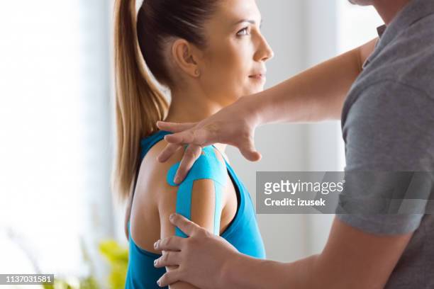 kinesio taping on woman's arm - kinesiotape stock pictures, royalty-free photos & images