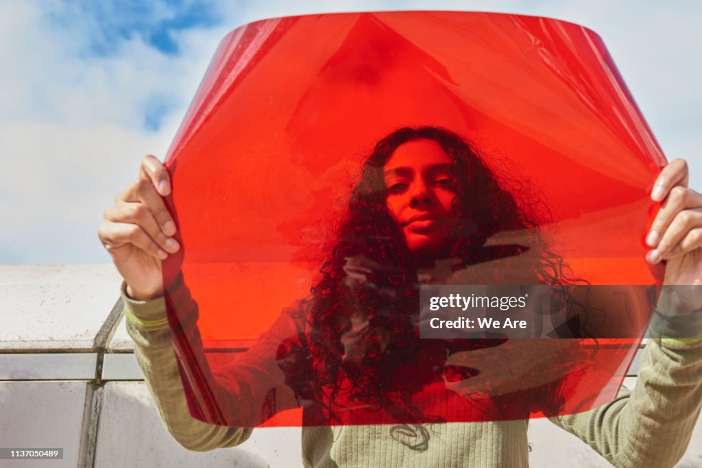 Young woman holding up red filter in front of face
