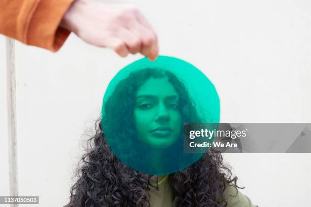 portrait of young woman shot through green cellophane - things that are round stock-fotos und bilder
