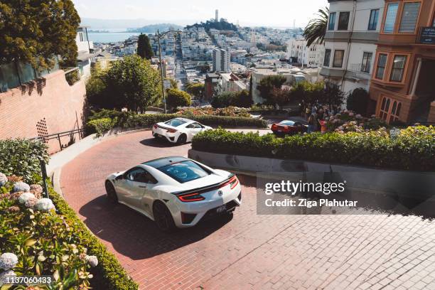 view from the top of lombard street, luxury cars driving down the curvy street - lombard street san francisco stock pictures, royalty-free photos & images