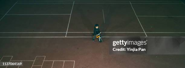 portrait of a little boy wearing sports helmet and riding bicycle at night - aerial view of childs playground stock pictures, royalty-free photos & images