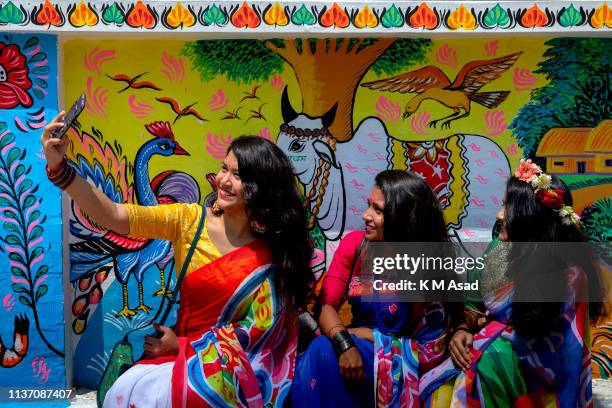 Bangladeshi student taking a selfi in front of the painted wall also come to attend a rally to celebrate the Bengali New Year or 'Pohela Boishakh...