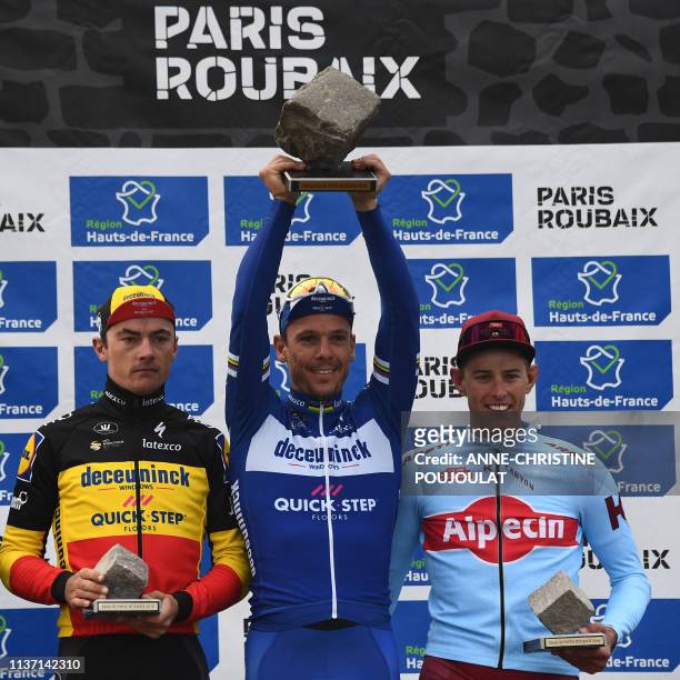Winner Belgium's Philippe Gilbert celebrates his trophy next to second-placed Germany's Nils Politt and third-placed Belgium's Yves Lampaert on the...