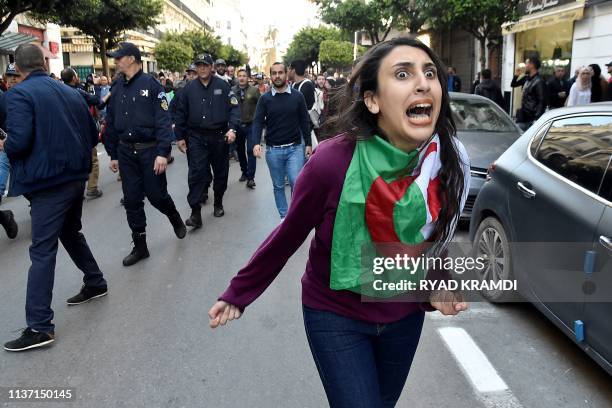 An Algerian woman wearing her national flag shouts as protesters demonstrate near Emir Abdelkader square in Algiers on April 14, 2019. Mass protests...