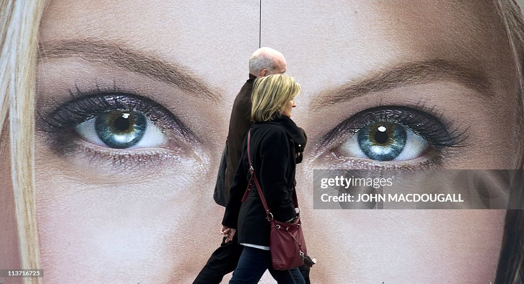 A couple walks past an advertising billb