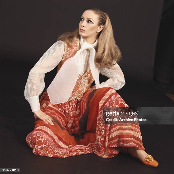 Model wearing a long patterned skirt with a white blouse, an embroidered waistcoat and a white scarf, 1969.