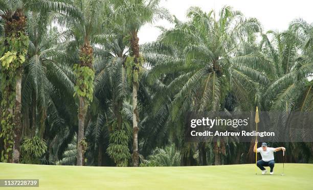 Marcus Fraser of Australia lines up a putt on the ninth hole on Day One of the Maybank Championship at Saujana Golf & Country Club, Palm Course on...