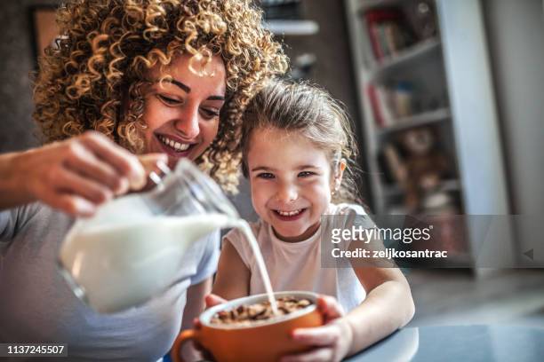 portret van schattige jonge meisje en moeder met ontbijt - familie eten stockfoto's en -beelden