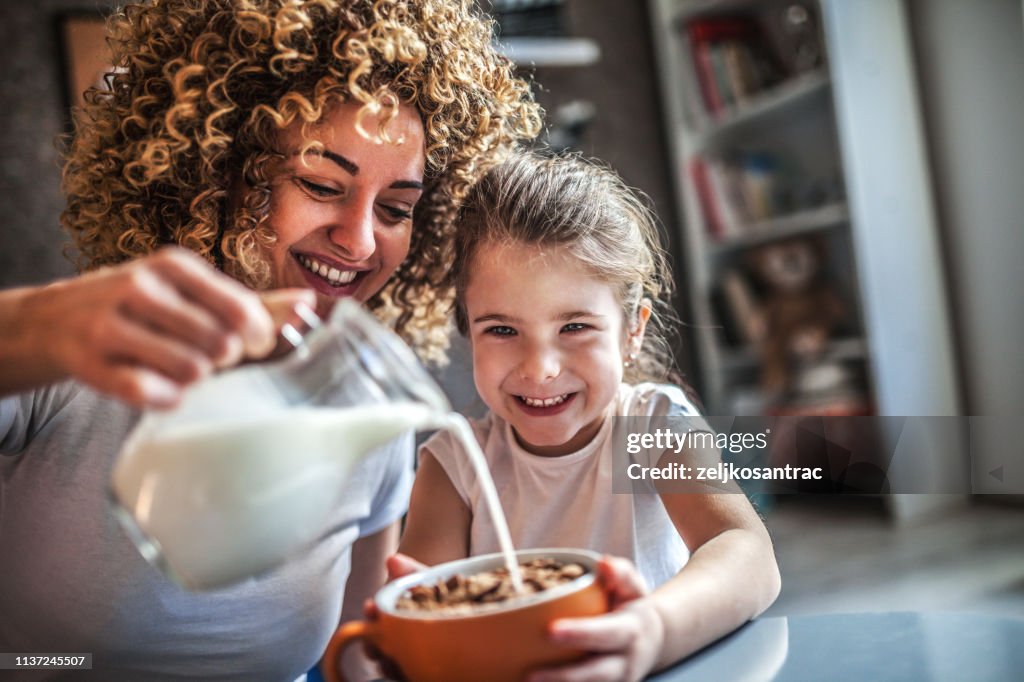 Portrait of adorable young girl and mother having breakfast