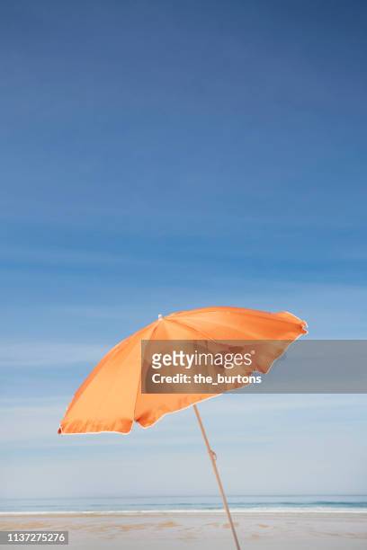 orange parasol on the beach against blue sky - beach umbrella stock pictures, royalty-free photos & images